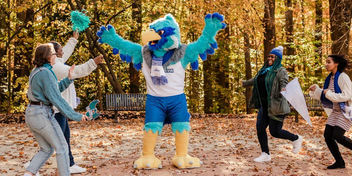 A group of students looking at AACC mascot, Swoop.